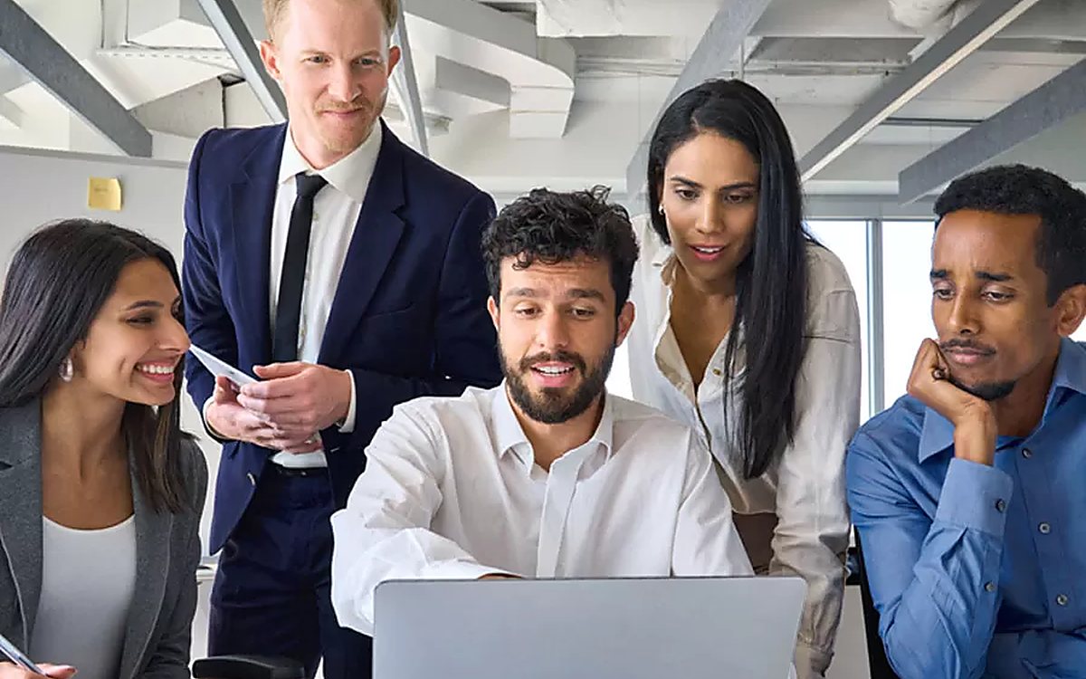 A support team gathered around a laptop in an office
